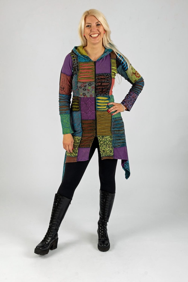 May include: A long, patchwork hooded jacket in various colours, including purple, green, and brown. The jacket features a zip closure and is worn with black leggings and knee-high black boots. The overall style is bohemian.