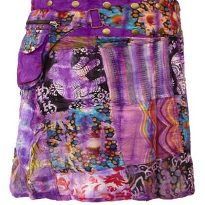 May include: A purple patchwork skirt with a tie belt and a large pocket on the side. The skirt is made of various fabrics with different patterns, including floral, paisley, and geometric designs.