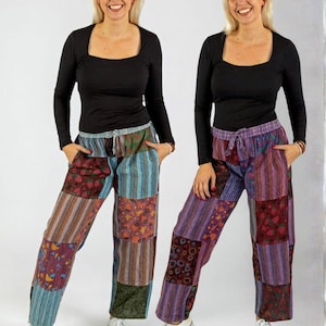 May include: Two people wearing black long-sleeve shirts and patchwork pants. The pants feature a variety of colors and patterns, including stripes, floral designs, and geometric shapes. White sneakers complete the look.