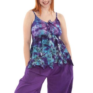 May include: A tie-dye tank top in shades of purple and turquoise with spaghetti straps and a drawstring neckline. The top is paired with purple pants. The top features a floral pattern and a ruffled hem.