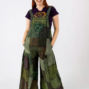May include: Green patchwork overalls with wide legs and front pockets. The overalls have adjustable straps and a front bib pocket. The model is wearing a purple t-shirt with a graphic design and white sneakers.