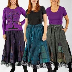 May include: Three women modeling long skirts with patchwork designs and lace trim. The skirts are paired with various tops, including a purple long-sleeve shirt with a tree design, a black t-shirt, and a purple short-sleeve shirt. The skirts have a drawstring waist.