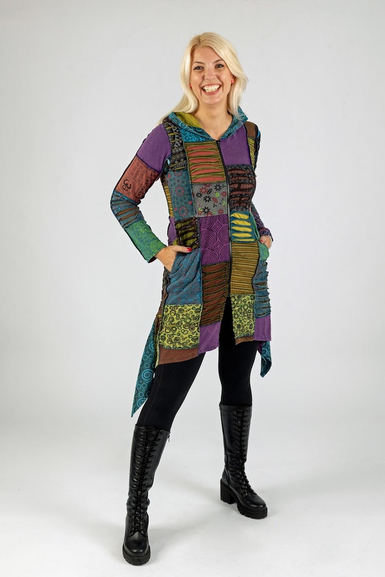 May include: A patchwork hooded jacket in shades of purple, green, and brown. The jacket features a variety of patterned fabric squares, a hood, and pockets. The person is wearing black leggings and black knee-high boots.