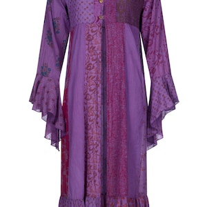 Pode incluir: Um vestido longo e fluido roxo com decote em V e mangas compridas com punhos largos. O vestido apresenta um design de patchwork com estampas florais e geométricas e uma bainha com babados. Possui botões de madeira na frente.