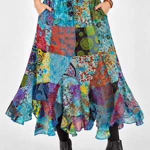 Può includere: Una gonna lunga e fluida in patchwork caratterizzata da un mix vivace di pannelli in tessuto blu, turchese, viola e verde con vari motivi floreali, geometrici e paisley. La gonna presenta una vita elasticizzata con coulisse e due tasche laterali.