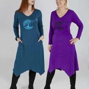 Könnte beinhalten: Zwei langärmlige V-Ausschnitt-Kleider, eines in Türkis und eines in Lila, jeweils mit einem Lebensbaum-Motiv. Die Kleider haben einen asymmetrischen Saum in Knielänge und Taschen. Beide werden mit schwarzen kniehohen Stiefeln getragen.