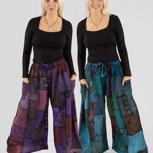 Op de afbeelding: Twee broeken met wijde pijpen en patchwork in paars en blauwgroen. De broeken hebben een tailleband met trekkoord en zakken. De modellen dragen zwarte tops met lange mouwen en witte sneakers. Het patchwork heeft verschillende patronen en texturen.