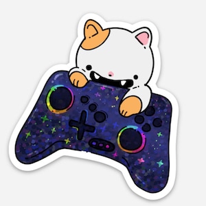 May include: A white cat with orange ears is holding a black and blue video game controller with rainbow accents and a starry pattern.