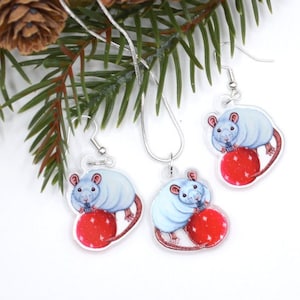 May include: A set of silver earrings and a necklace featuring a white rat holding a red Christmas ornament. The rat is depicted in a cartoon style.