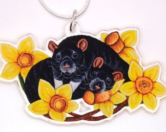 May include: A silver chain necklace with a black acrylic pendant featuring two black rats nestled in yellow daffodils.