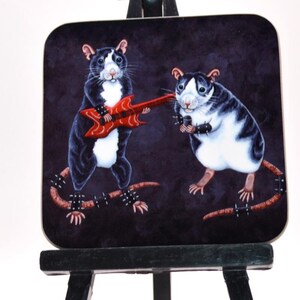 Puede incluir: Un posavasos cuadrado con un fondo oscuro que representa dos ratas de dibujos animados. Una rata toca una guitarra roja y la otra lleva una pulsera con tachuelas. Ambas ratas tienen pelaje blanco y negro y posan como si estuvieran en una banda de rock.