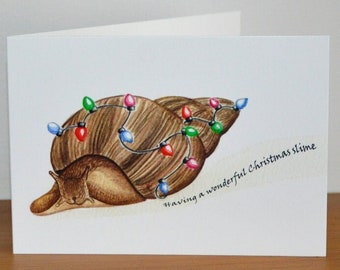 May include: A Christmas card featuring a snail with a shell decorated with colorful Christmas lights. The text on the card reads "having a wonderful Christmas slime".