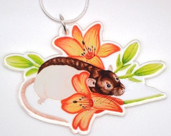 May include: A silver chain necklace with a clear acrylic pendant featuring a brown and white rat nestled in orange lily flowers.