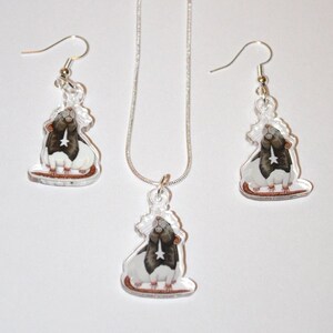 May include: A silver necklace and earrings set featuring a black and white rat charm. The rat is depicted in a sitting position with its head tilted up.