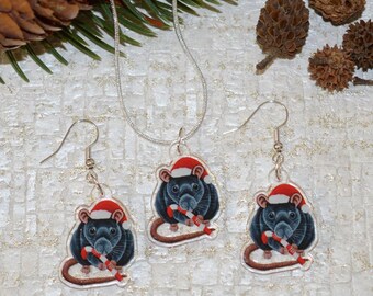 May include: A set of Christmas-themed jewellery featuring a black rat wearing a Santa hat and holding a candy cane. The set includes a necklace and a pair of earrings.