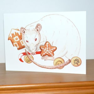 May include: A greeting card featuring a white rat with red eyes, surrounded by festive elements. The illustration includes a gingerbread house, a star-shaped cookie, candy cane, and coins. The card is set against a white background.