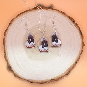 May include: A silver necklace and earrings set featuring a black and white rat design. The rat is depicted with a star on its chest and is set against a clear background.