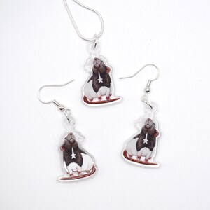 May include: A set of silver rat earrings and a necklace. Each piece features a black and white rat with a star on its chest, looking up.