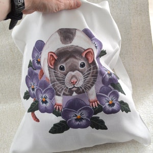 May include: White pillowcase with a watercolour illustration of a rat and purple pansies. The rat has grey and white fur, pink ears and nose. The pansies have dark purple petals and yellow centres.