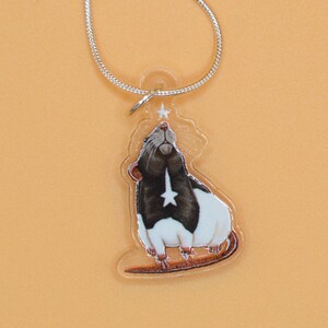 May include: A silver chain necklace with a clear acrylic pendant featuring a black and white rat looking up at a white star.