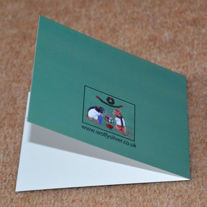 May include: A green folded card with a white interior. The front of the card features a small illustration of two mice wearing hats and holding gifts. The text "www.wolfysilver.co.uk" is printed below the illustration.