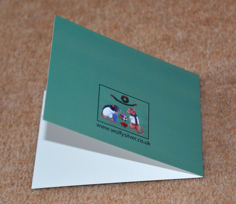 May include: A green folded card with a white interior. The front of the card features a small illustration of two mice wearing hats and holding gifts. The text "www.wolfysilver.co.uk" is printed below the illustration.