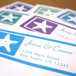 May include: A blue and white wedding invitation with a starfish design. The invitation reads "Jenna & Connor" and includes the address "1234 Main Street, Any Town, US 12345".
