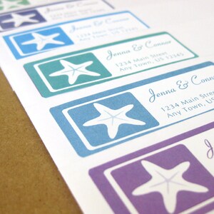 May include: A set of five address labels with a white starfish design on a blue, green, purple, and teal background. The labels have the text "Jenna & Connor" and an address on them.