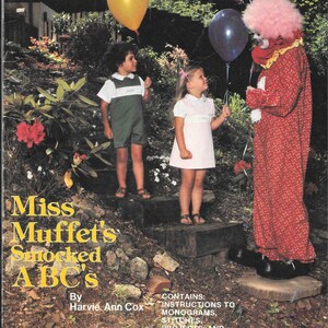 May include: A book cover with the title "Miss Muffet's Smocked ABC's" by Harvie Ann Cox. The cover features a colorful illustration of children and a clown with balloons in a garden setting. The book contains instructions for smocking, monograms, stitches, projects, and a stocking pattern.