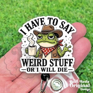 May include: A white badge reel with a cartoon frog wearing a cowboy hat, vest, and red bandana, holding a coffee cup. Text reads "I HAVE TO SAY WEIRD STUFF - OR I WILL DIE-".