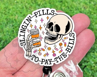 May include: A white badge with the text "SLINGIN' PILLS TO PAY THE BILLS" encircling a skull and a skeleton hand holding a pill bottle. The design includes stars and pills in pink, orange, and yellow.