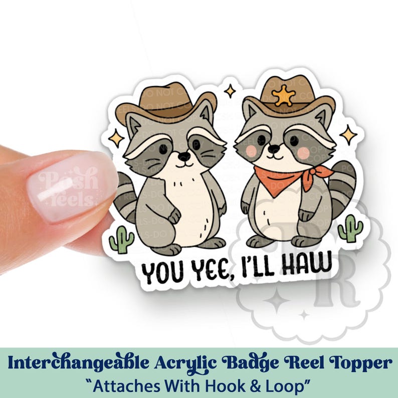May include: A sticker featuring two cartoon raccoons wearing cowboy hats and bandanas. One raccoon has a sheriff's badge. The text reads "YOU YEE, I'LL HAW". The sticker is an interchangeable acrylic badge reel topper.