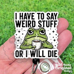 May include: A white badge reel with a cartoon frog holding a coffee cup. The frog is green with black spots and large eyes. Text on the badge reads "I HAVE TO SAY WEIRD STUFF OR I WILL DIE."