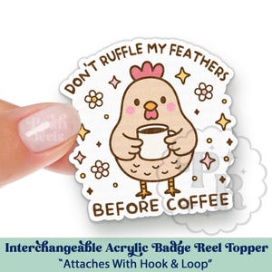 May include: An interchangeable acrylic badge reel topper featuring a cartoon chicken holding a coffee cup. The text reads "DON'T RUFFLE MY FEATHERS BEFORE COFFEE". The design includes flowers and stars.