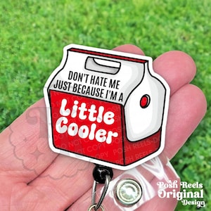 May include: A white and red badge reel with the text "DON'T HATE ME JUST BECAUSE I'M A Little Cooler." The badge reel is in the shape of a cooler and has a black retractable cord and a clear plastic clip.
