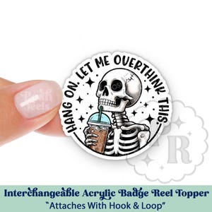May include: A round, white acrylic badge reel topper featuring a skeleton holding an iced coffee. The text reads "HANG ON. LET ME OVERTHINK THIS." The topper is designed to attach with hook and loop.