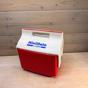May include: A red and white MiniMate cooler by Igloo. The cooler has a white top with a red handle and a red lower section. The words "MiniMate by Igloo" are printed in blue on the front of the cooler.