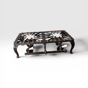 May include: A vintage, cast iron two-burner stove top with white knobs. The stove top is dark gray with a rectangular shape and four curved legs. The burners are star-shaped.