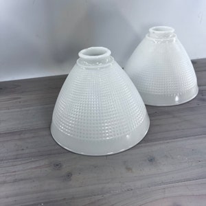 May include: Two white glass lampshades with a textured, diamond-shaped pattern. The lampshades are cone-shaped and have a white, opaque finish.