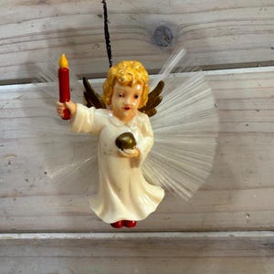 A vintage Christmas ornament depicting an angel holding a candle, Vintage angel with candle Christmas ornament, Made in West Germany, MCM