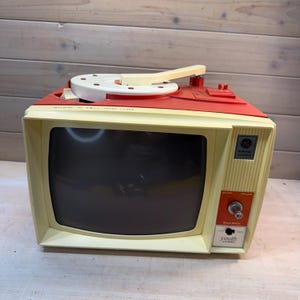 May include: A white ceramic mug with a black handle and the text "But First, Coffee" in a black, handwritten-style font. The mug is on a white surface.