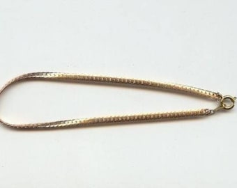 May include: A gold chain necklace with a delicate, textured design. The chain is made of two-toned metal, with a lighter gold color on one side and a darker gold color on the other.