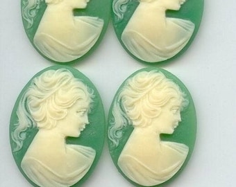 May include: Four oval-shaped green cameo pendants with white raised images of women's profiles. The women have detailed hairstyles and are wearing simple dresses.