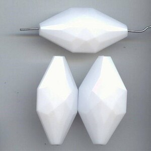 May include: Three white faceted glass beads. The beads are shaped like a teardrop with a pointed end and a rounded base. The beads are approximately 1 inch in length.