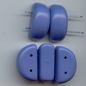 May include: A set of six blue plastic beads with two holes each. The beads are in two different shapes, one is a half-circle and the other is a rectangle.