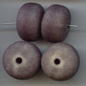 May include: Four purple and white donut-shaped beads with a hole in the center. The beads are made of a textured material.