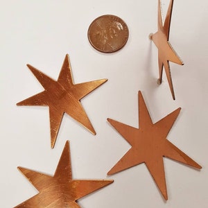 May include: Four copper eight-pointed stars on a white background. The stars are approximately the size of a US quarter.