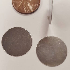May include: Three silver-colored metal discs, each about the size of a US penny. The discs are smooth and have a slightly textured surface.