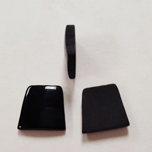 May include: Three black rectangular shaped buttons. The buttons are made of a smooth, glossy material.