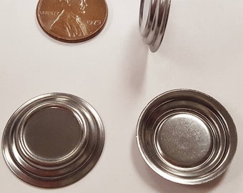 May include: Three silver metal lids with a raised rim and a slightly domed center. The lids are about the size of a US penny.